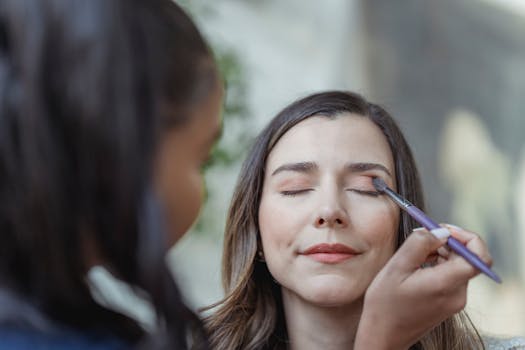 Close-up of a professional makeup artist applying eyeshadow to a client indoors.